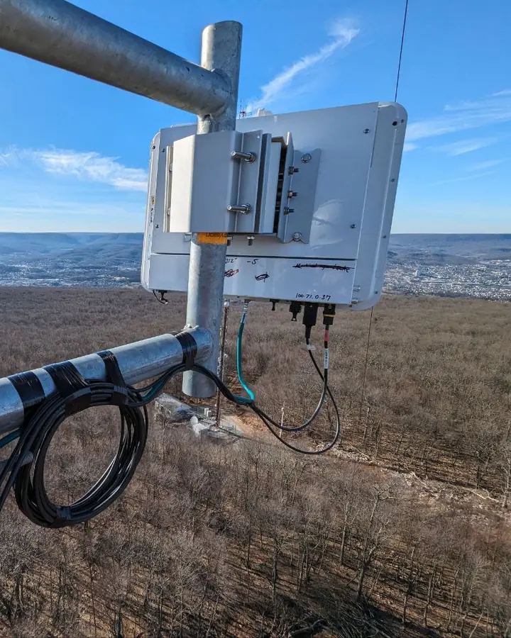 A modern base-station radio on a Crowsnest tower mast high above an autumn valley and town.