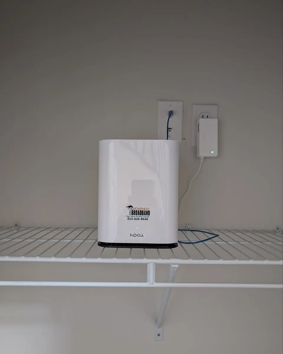 A white whole-home Wi-Fi unit with a Crowsnest sticker on a wall shelf.