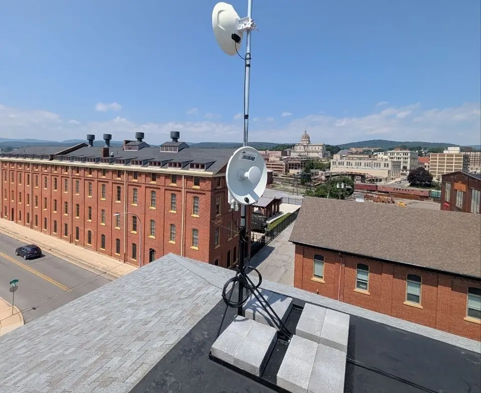 Rooftop radio dishes above a downtown of historic brick buildings and a domed cathedral.