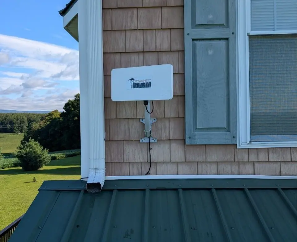 A Crowsnest radio on a shingled wall above a green metal porch roof.