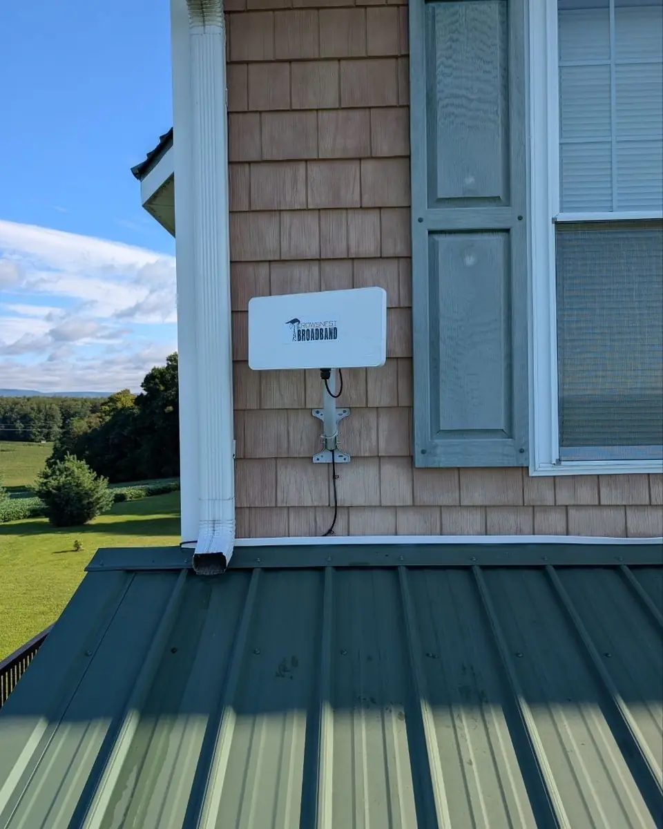 A Crowsnest radio on a shingled wall above a green metal porch roof.