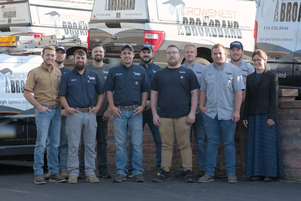 The Crowsnest Broadband team standing together in front of Crowsnest service trucks.